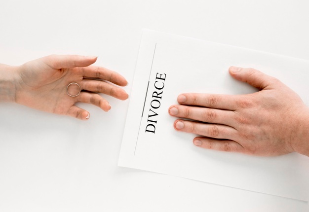 Procedure de divorce représenté par une main masculine posée sur un contrat et une main féminine avec une alliance